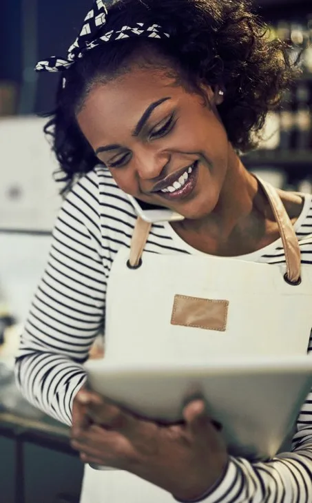 Small business owner on a call while checking a tablet in her shop